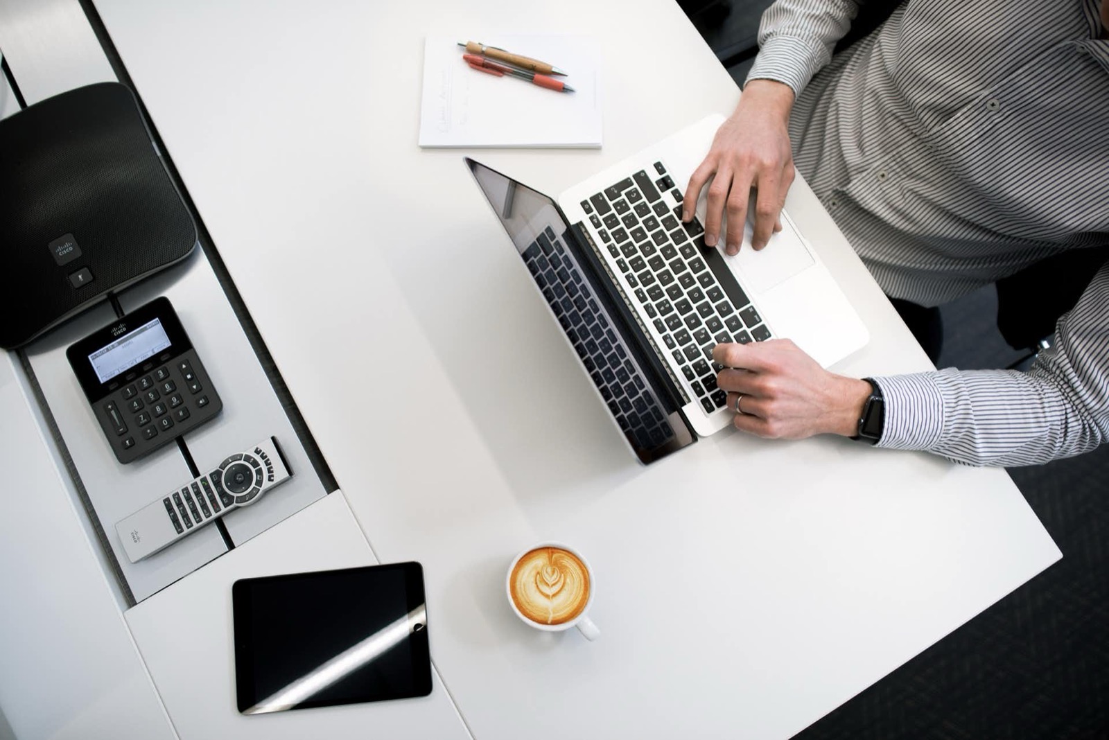 Arbeitsplatz mit Laptop, Telefon und Kaffee von oben
